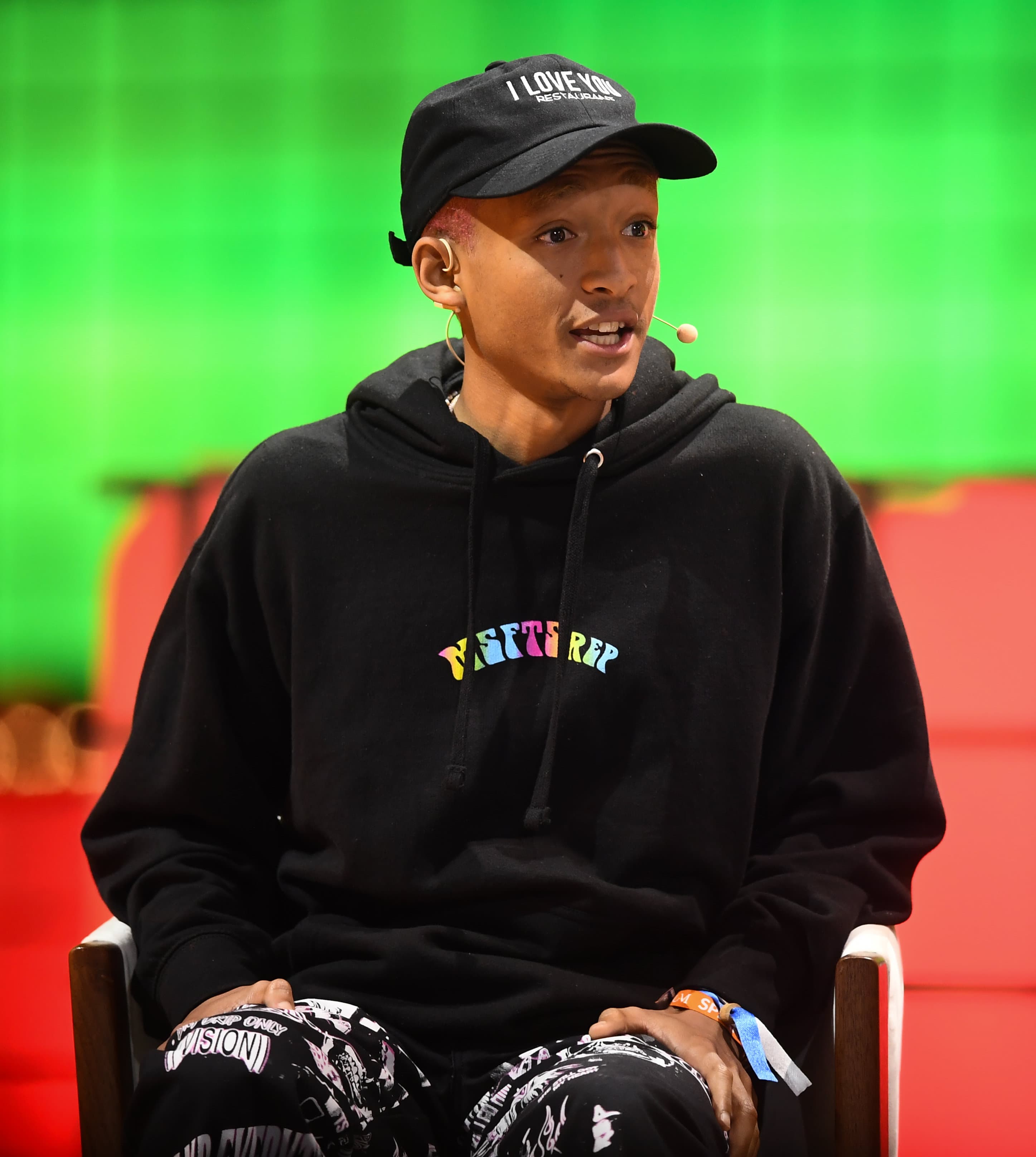Jaden Smith speaking onstage in a black cap and hoodie at Web Summit in 2019